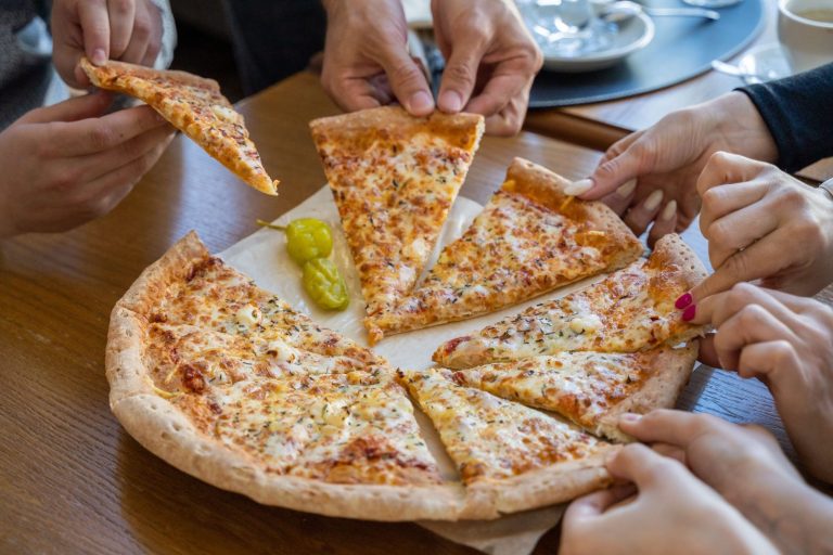 Grupo de amigos compartiendo una pizza en la mesa